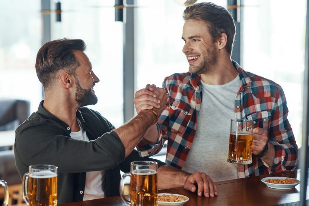 Two young men in casual clothing handshaking and smiling