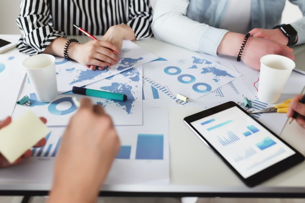 Business planning, colleagues sitting at table with different graphics, charts